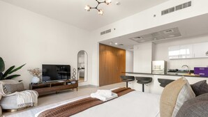 Ett modernt hotellrum med en säng, en TV, ett skrivbord och ett litet pentry.