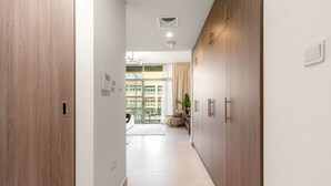 En modern hall med träskåp, ett ljust kaklat golv och utsikt över ett vardagsrum med soffa och gardiner.