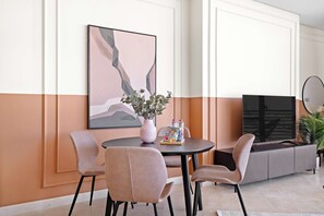 Un comedor moderno con una mesa redonda, cuatro sillas, un florero con follaje y un cuadro en la pared.