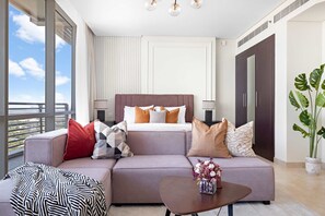 A modern hotel room with a large bed, a sofa, a coffee table with flowers, and a view of the outdoors. - Silkhaus Chic Studio Sky Gardens Difc (Dubai)