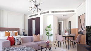 A modern hotel room with a large bed, a sofa, a dining table with chairs, and a TV. - Silkhaus Chic Studio Sky Gardens Difc (Dubai)