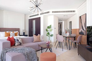 A modern hotel room with a large bed, a sofa, a dining table with chairs, and a TV. - Silkhaus Chic Studio Sky Gardens Difc (Dubai)