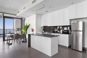 A modern kitchen with a central island, stainless steel appliances, and a view to the outside. - Silkhaus Unique 2bdr Beach Access in Pixel Tower (Abu Dhabi)