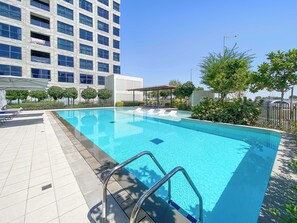 A swimming pool with a tiled deck, a metal ladder, and lounge chairs. - Silkhaus Unique 2bdr Beach Access in Pixel Tower (Abu Dhabi)