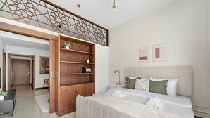 Une chambre moderne avec un grand lit, une bibliothèque en bois, un bureau et un escalier.