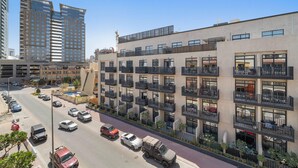 Un hôtel à plusieurs étages doté de balcons, d’un parking et entouré d’immeubles de grande hauteur.