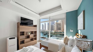 Een moderne hotelkamer met een groot raam, een flatscreen televisie, een verwarming en een bed met witte lakens.