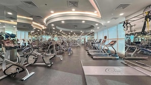 Een moderne sportschool met diverse fitnessapparaten, waaronder loopbanden en krachttoestellen, in een ruime opstelling.