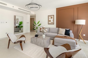 Ein modernes Wohnzimmer mit einem grauen Sofa, zwei Sesseln, einem Couchtisch und einer Stehlampe.