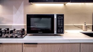 A kitchen with a black Panasonic microwave, a gas stove, and a sink. - Stayshort - Stunning Studio Unit in Business Bay That Sleeps 2 (Dubai)
