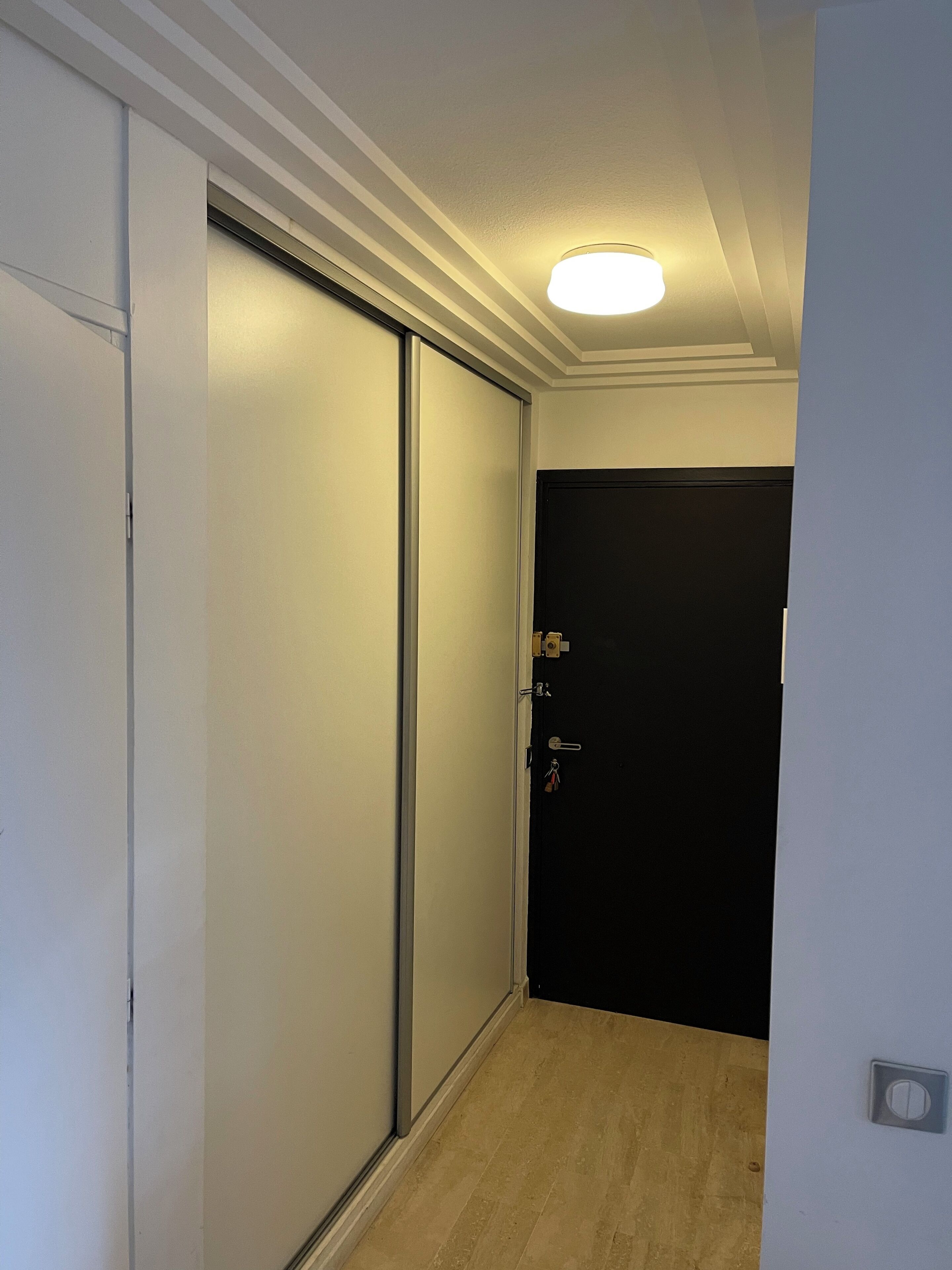 A narrow hallway with a sliding door on the left and a closed door on the right.