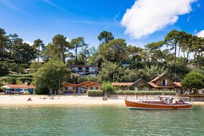 Un hôtel situé sur la côte, composé de plusieurs bâtiments, avec une plage et un bateau.