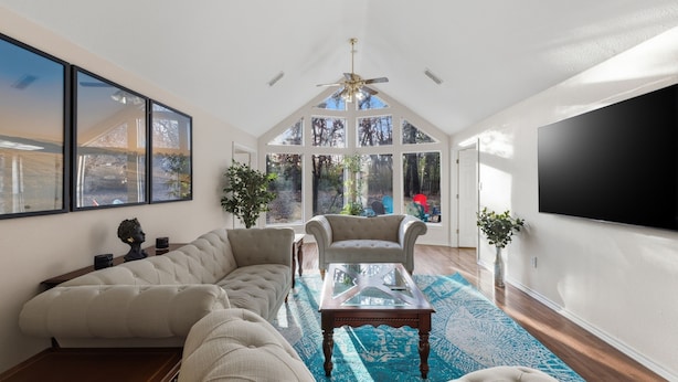 A spacious living room with a sectional sofa, a glass coffee table, and a large TV. - Oakwood Oasis: 1.4 Acres Of Tranquility 6 Bedroom Home (Denton)