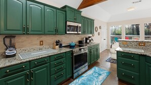 A kitchen with green cabinets, a built-in oven, and a coffee maker. - Oakwood Oasis: 1.4 Acres Of Tranquility 6 Bedroom Home (Denton)