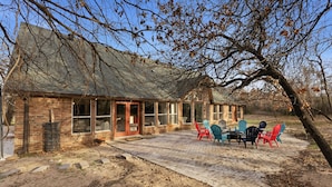 A brick building with a covered patio and outdoor seating area. - Oakwood Oasis: 1.4 Acres Of Tranquility 6 Bedroom Home (Denton)