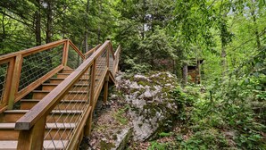 A wooden bridge with metal railings in a forested area. - Mountain Joy 1 Bedroom Cabin (Sevierville)