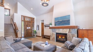 A spacious living room with a fireplace, a large sofa set, and a staircase leading to another level. - Schaffer's Mill - Chaparral 4 Bedroom Home (Truckee)