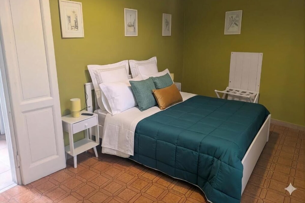 Un dormitorio con cama, mesita de noche y una silla.