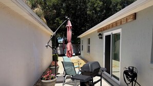 Een terras met een barbecue, stoelen en een bloempot.