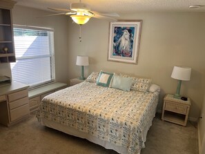 A bedroom with a bed, two bedside tables with lamps, a ceiling fan, a window with blinds, and a framed picture on the wall. - Cozy, pet-friendly in Village of De La Vista, golf cart, sunny & grill-ready. (The Villages)