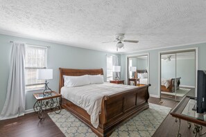 A bedroom with a wooden bed, a ceiling fan, a nightstand, a lamp, a mirror, and a television. - Cloud Nine on Lake Murray-SUPs, Game Room and More (Prosperity)