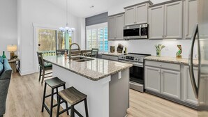 Eine moderne Küche mit Granit-Arbeitsplatten, Edelstahlgeräten und einer großen Kochinsel mit Barhocker.