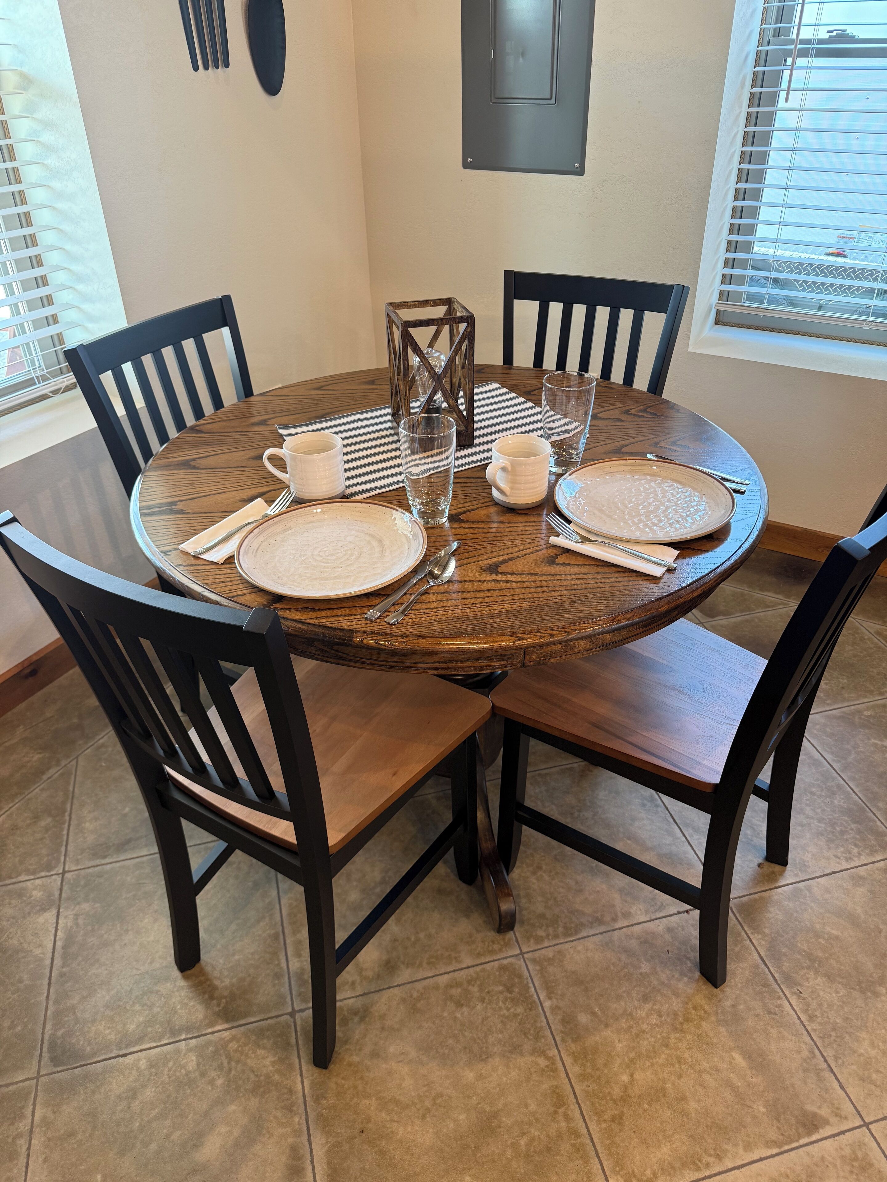 A round dining table with four chairs, a candle, and glassware.