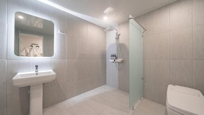 A modern bathroom with a pedestal sink, a glass shower enclosure, and a toilet. - HOTEL LAVANDA (Incheon)