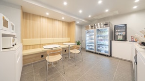 A modern kitchenette with a built-in oven, a refrigerator, and a microwave. There is a seating area with a bench and two chairs. - HOTEL LAVANDA (Incheon)