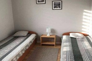 A small room with two single beds, a nightstand with a lamp, and a rug on the floor. - Holiday Home, Large Garden With Gazebo, Playground (Ustka)
