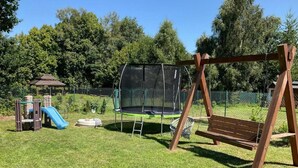 Ein Spielplatz mit Schaukeln, einer Rutsche und einem Trampolin.
