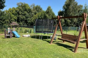 A playground with a swing set, slide, and trampoline. - Holiday Home, Large Garden With Gazebo, Playground (Ustka)