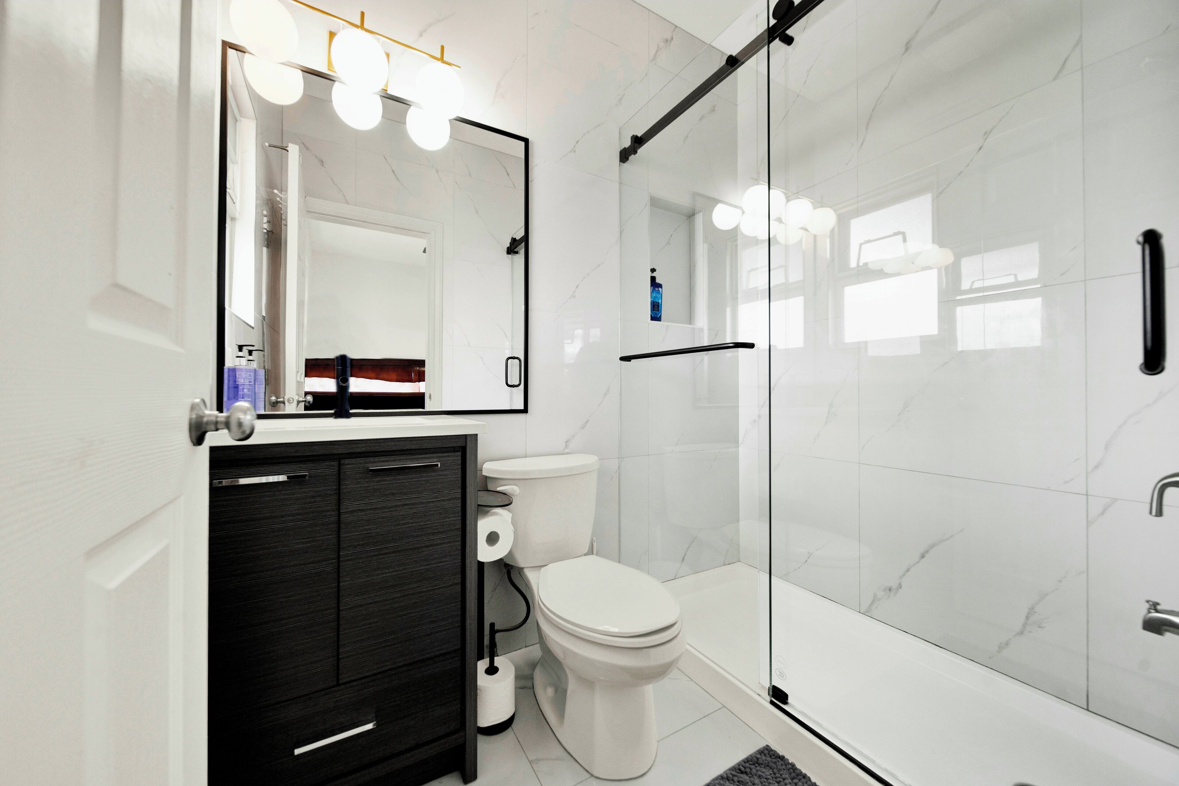 A modern bathroom with a glass shower enclosure, a white toilet, and a dark wood vanity.