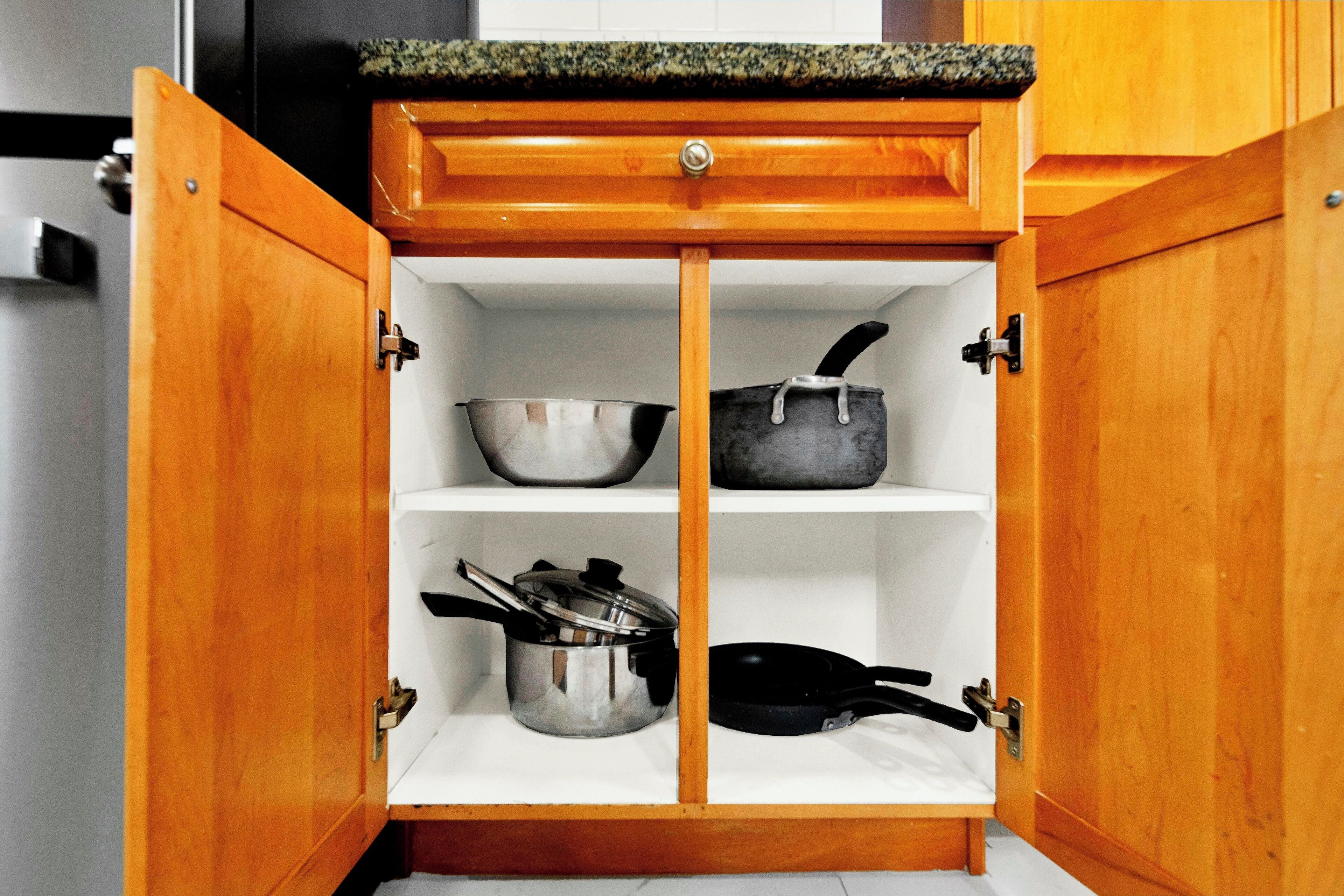 Un gabinete de madera con tres repisas, cada una con utensilios de cocina.