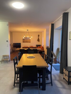 Un comedor moderno con una mesa de madera, sillas negras y una lámpara de araña.