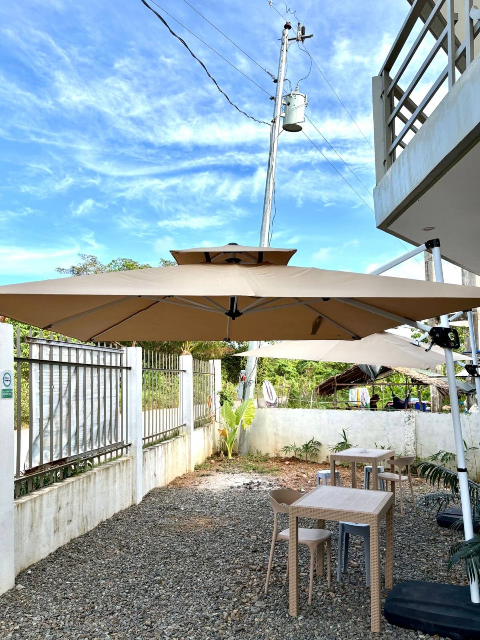 An outdoor patio area with a table and chairs, a covered seating area, and a metal fence.