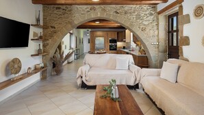 Un vaste espace de vie agrémenté d’une arche en pierre, d’un plafond en bois et d’un canapé confortable.