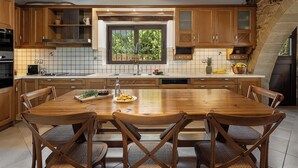 Une cuisine avec des meubles de rangement en bois, une grande fenêtre et une table à manger avec des chaises.