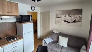 Een compacte leefruimte met een kitchenette, een eethoek en een bank.