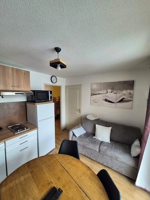 A compact living space with a kitchenette, a dining area, and a sofa. - 6-person apartment at the foot of the slopes (Les Orres)
