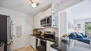 Een moderne keuken met witte kasten, een zwart aanrecht en roestvrijstalen apparatuur.