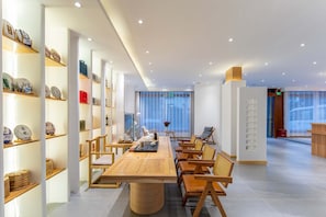 Un hall d’hôtel moderne avec un long comptoir d’accueil en bois, des sièges confortables et des étagères où sont exposés des objets décoratifs.