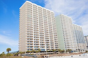 A multi-story hotel with a uniform exterior, balconies, and a flagpole. - Gulf-Front 2BR • Sleeps 6 • Ocean Villa 702 • Master w/Amazing Views (Panama City Beach)