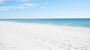 Ein Strand mit weißem Sand und klarem, blauem Wasser.