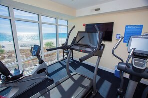 A fitness room with treadmills and a TV, overlooking a beach. - Gulf-Front 2BR • Sleeps 6 • Ocean Villa 702 • Master w/Amazing Views (Panama City Beach)