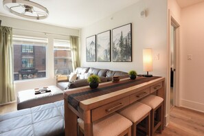 Habitación de hotel moderna con una cama, un sofá, un escritorio con lámpara y vistas a un edificio.