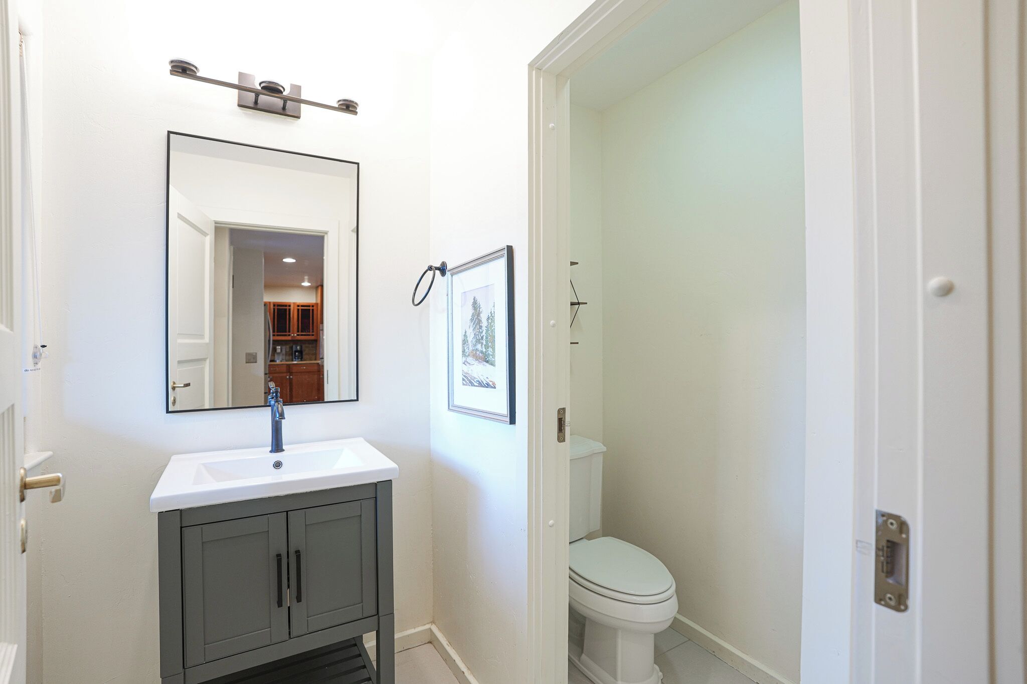 A bathroom with a white sink, a mirror, and a toilet.