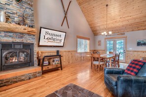 A cozy lodge interior with a fireplace, wooden dining table, and a comfortable seating area. - Sunriver Vacation Home, Hot Tub, Bikes, SHARC, Dog Friendly (Sunriver)