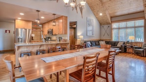 Une cuisine spacieuse dotée de meubles en bois, d’un grand îlot central et d’un coin repas avec une table et des chaises en bois.