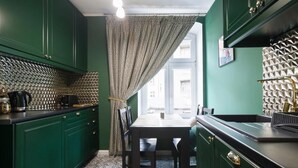 A kitchen with green cabinets, a patterned backsplash, and a dining table with chairs. - Malila Apartments Cracow Lubicz 14 (Kraków)